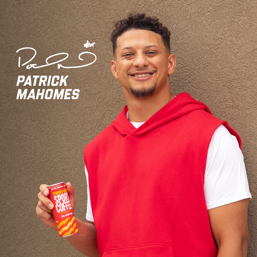 A smiling man in a red sleeveless hoodie holds a can from the Latte Variety 6-Pack, showcasing the bold energy of these Premium Charged Lattes. Patrick Mahomes and a signature appear in white text on the textured brown background.